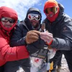 three mountaineers with a cross