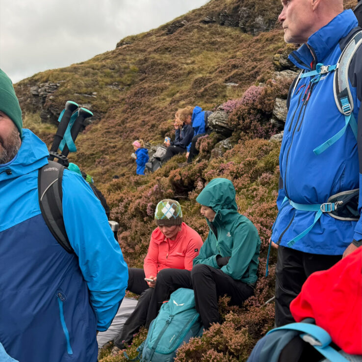  Mountain hikers supporting teammate during challenging ascent on Irish peak