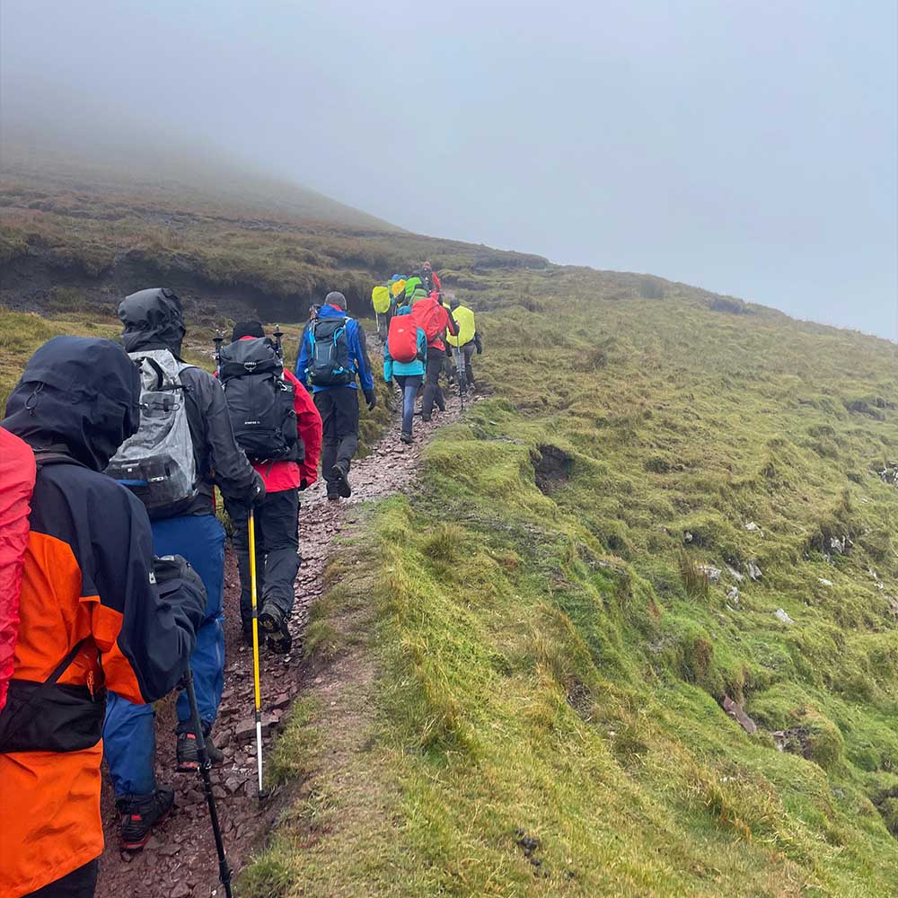 Corporate team demonstrating systems thinking and interdependence during mountain leadership challenge