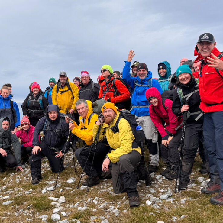 Victorious team celebrating together at Irish mountain summit after completing peak