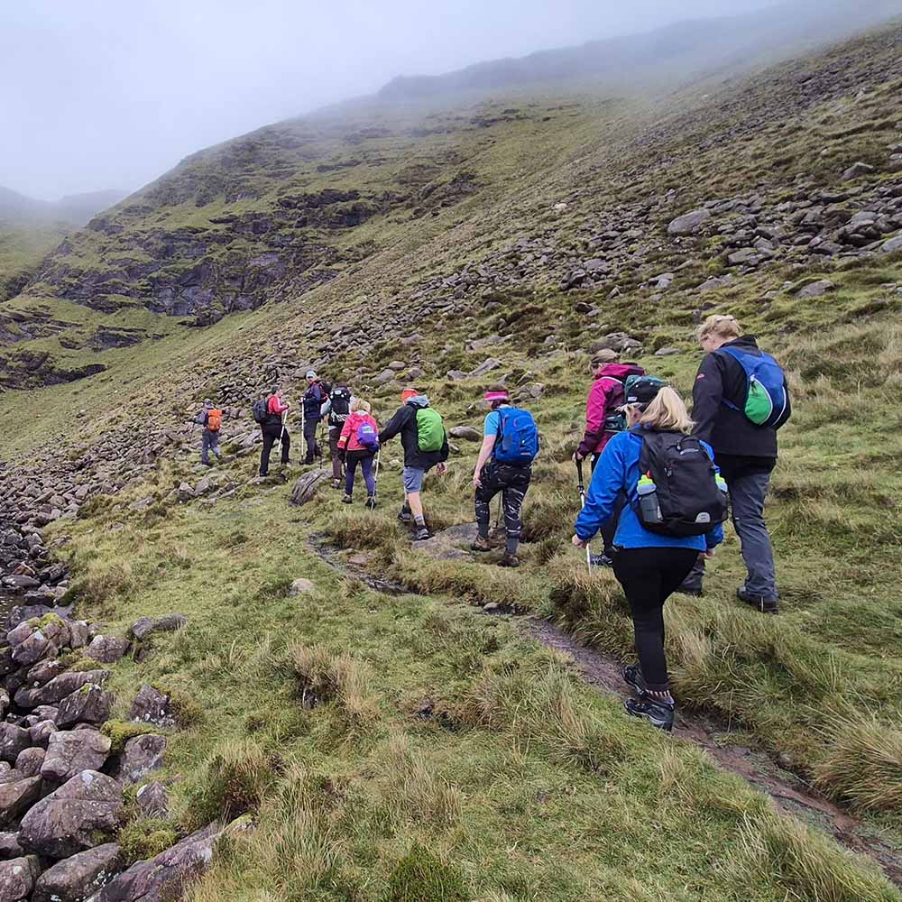 Small group of hikers on Irish mountain trail during multi-peak challenge