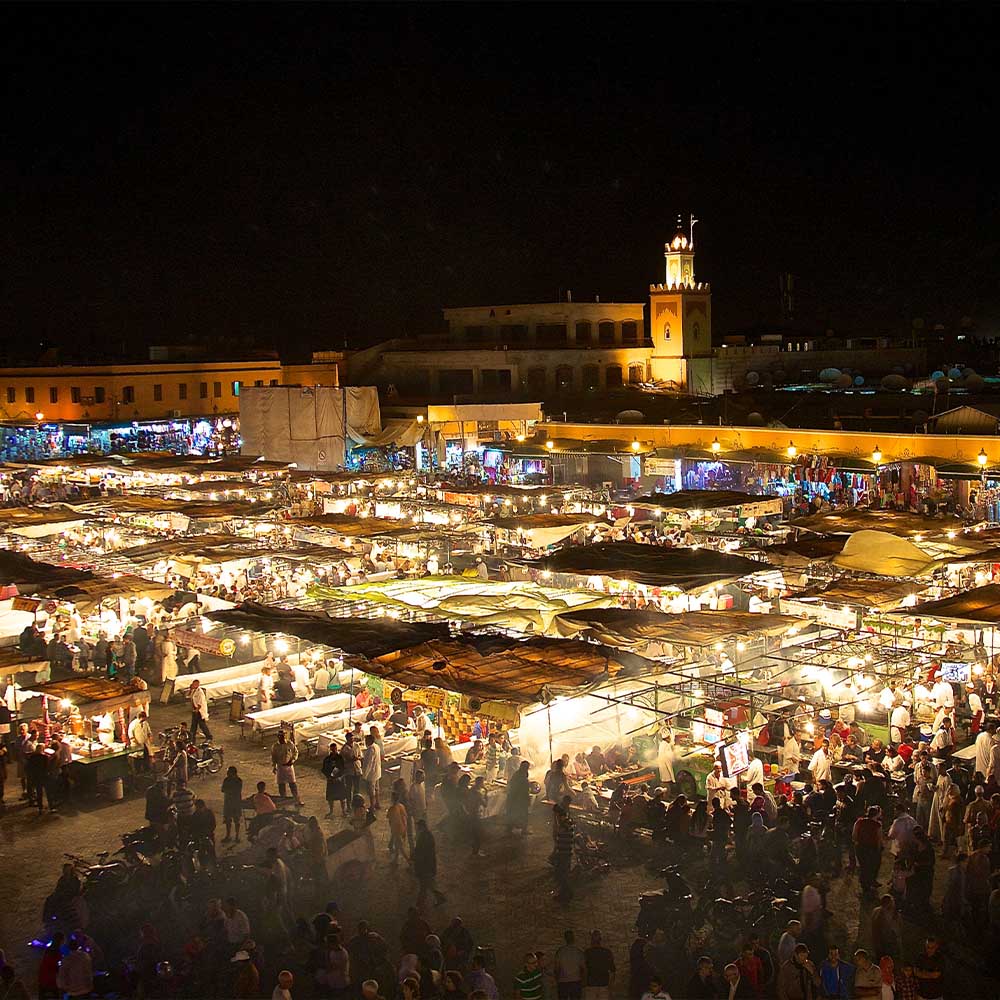 Jemaa el-Fna square in Marrakesh at dusk with market stalls and city lights