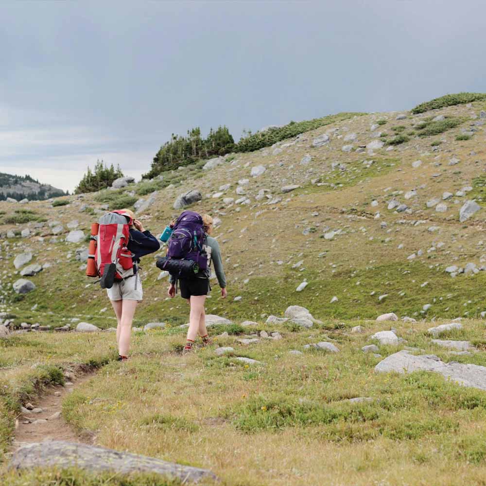 Trekker safely descending mountain trail after altitude sickness AMS symptoms guided expedition safety protocol
