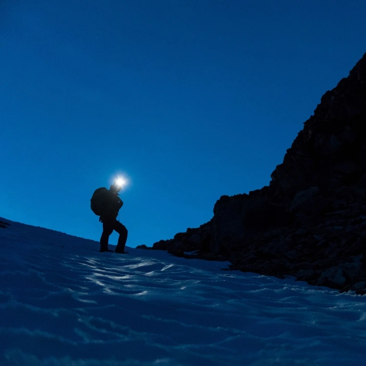 Women trekking up the South Cirque scree field toward Toubkal saddle in the pre-dawn dark with headtorches