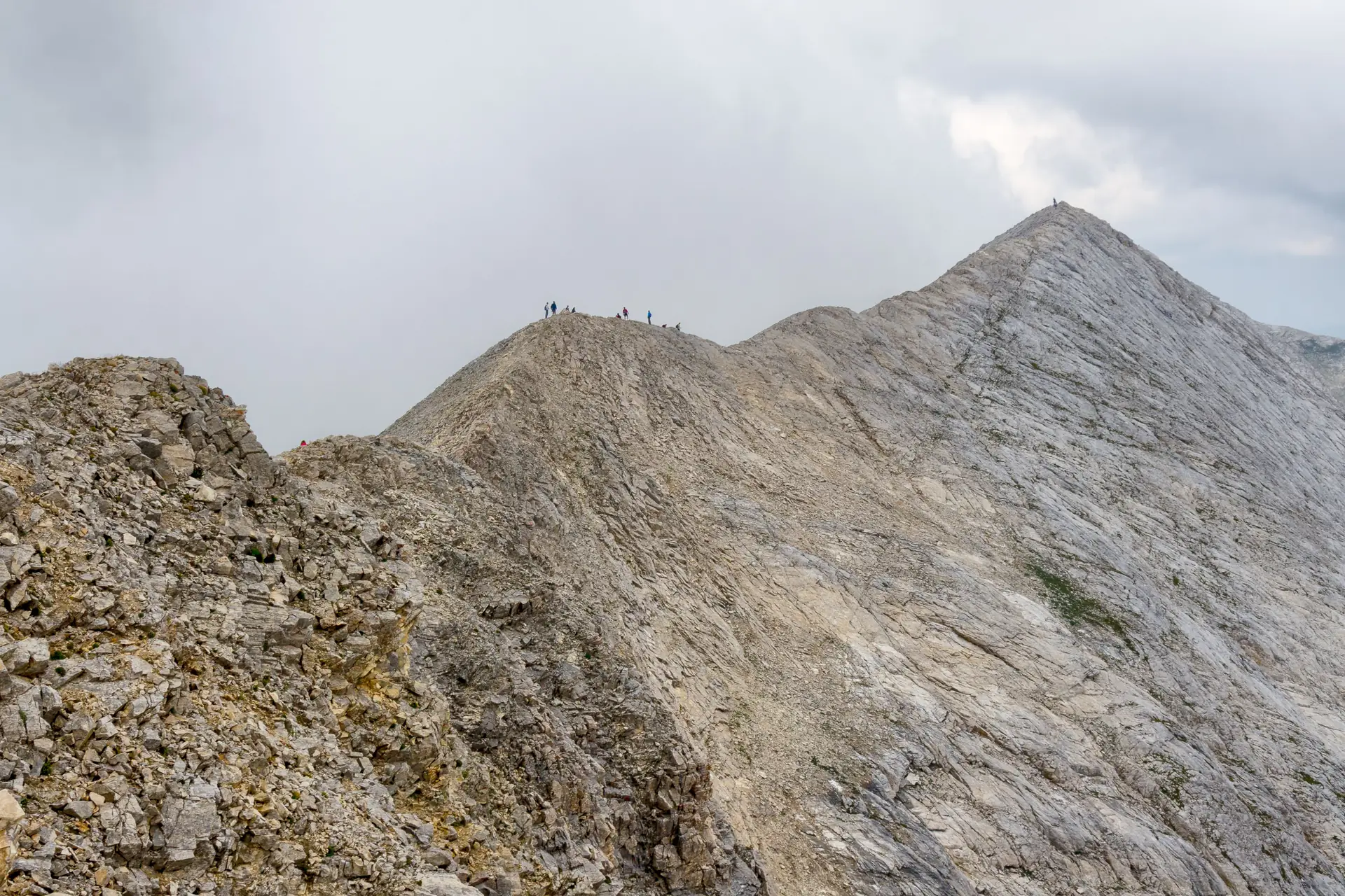 Hiker traversing Koncheto marble knife-edge ridge with fixed cables in Pirin Mountains Bulgaria