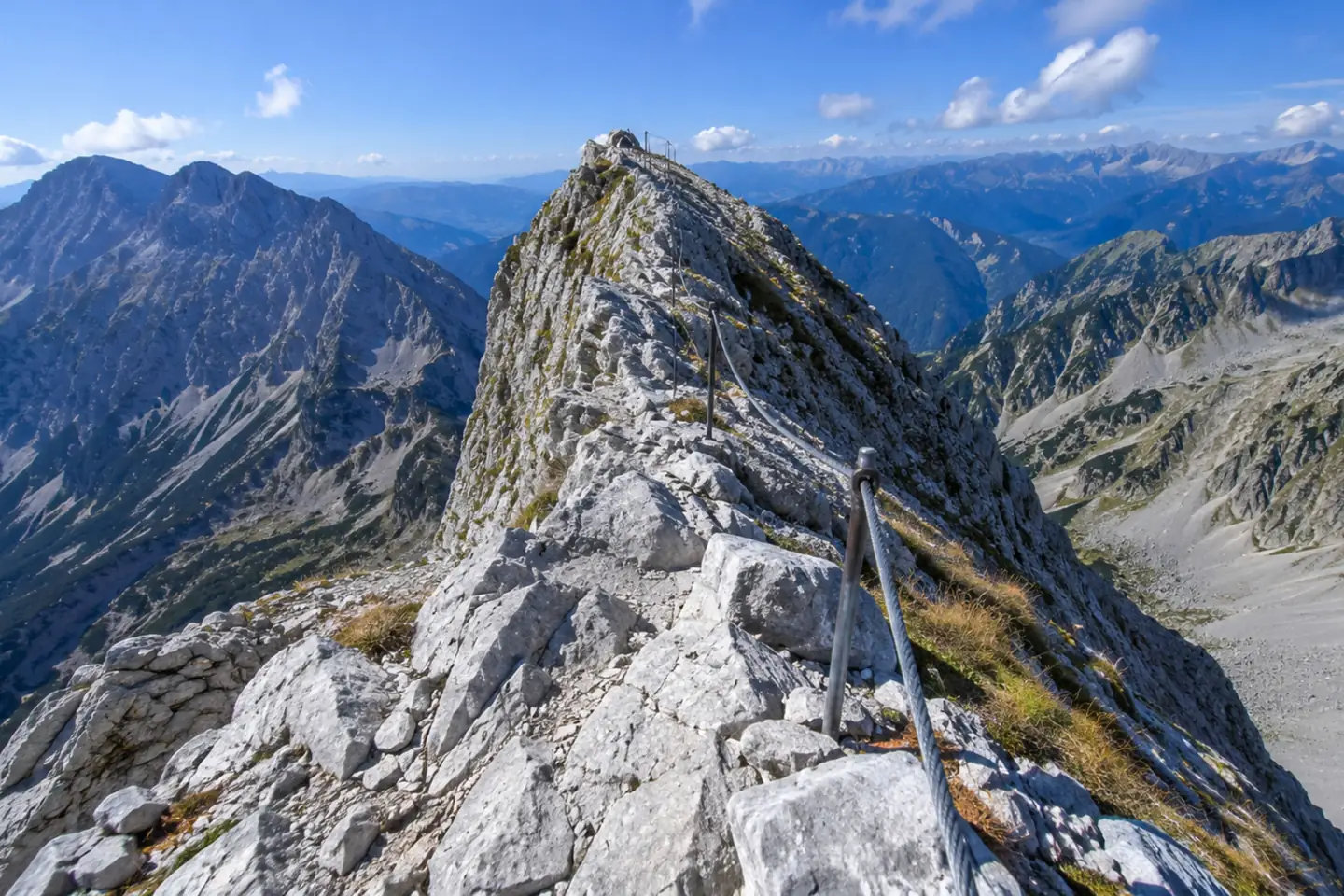 Hiker using fixed steel cables on exposed white marble Koncheto Ridge Pirin Mountains Bulgaria 7 Summits