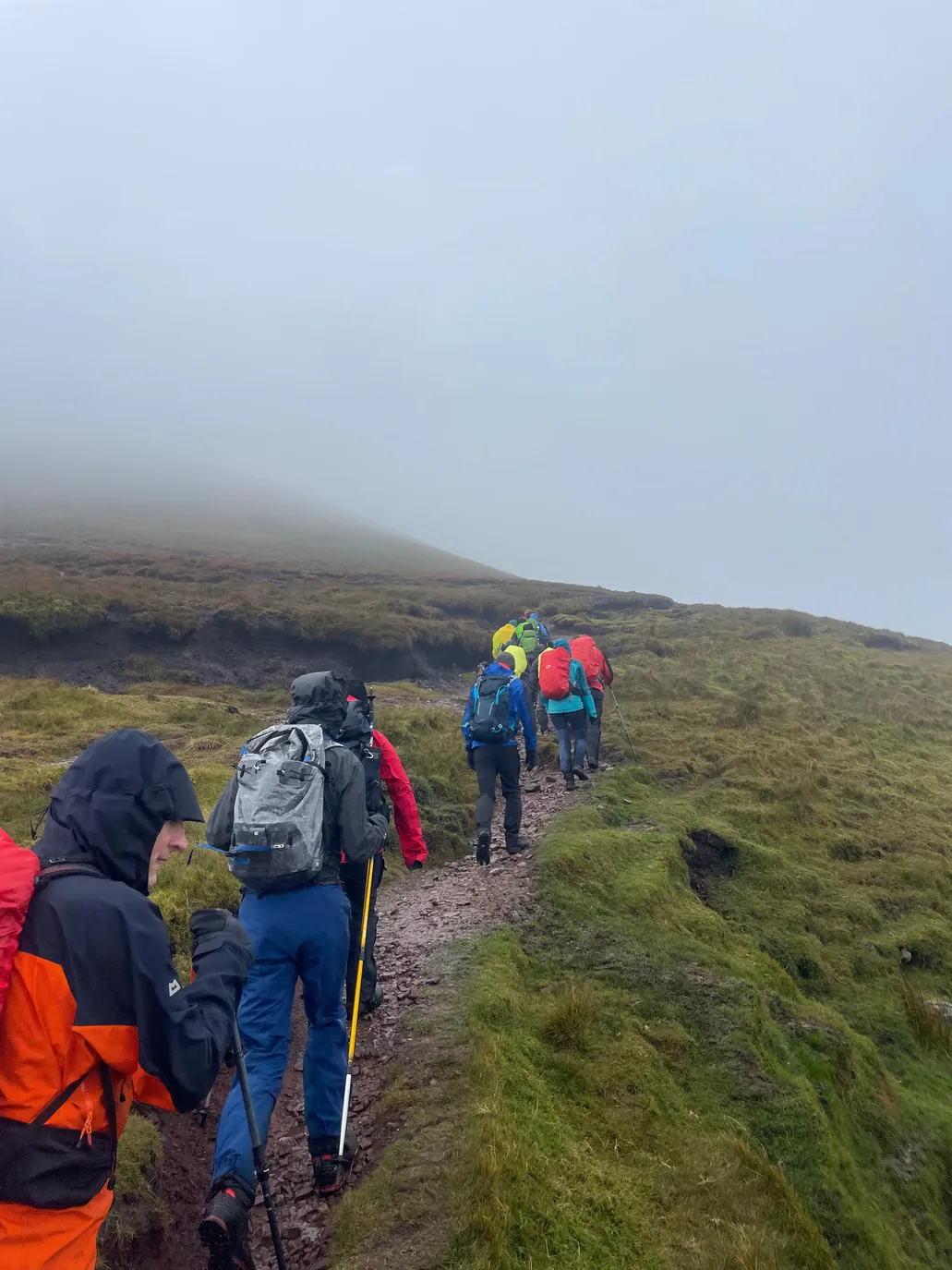 A tight-knit team moves together across exposed ridge terrain during an alpine ascent. Small mountaineering team ascending a ridge line together during a national summit challenge