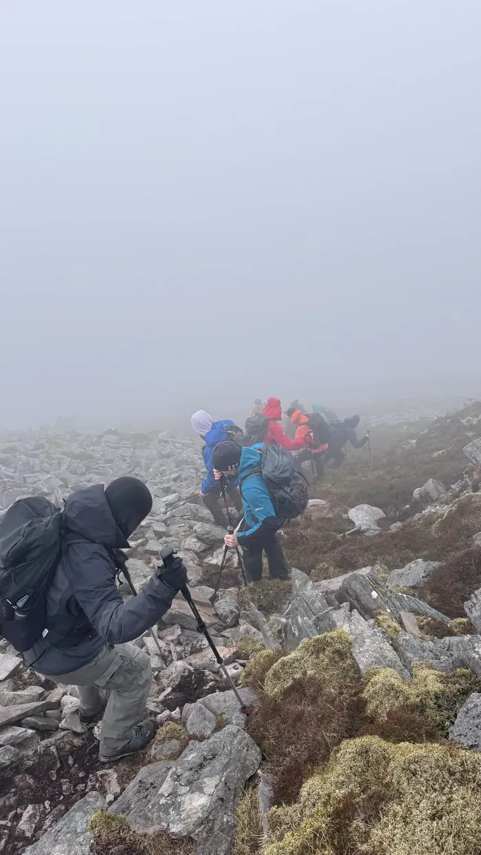 Mountain guide at the back of a small hiking group in cloud