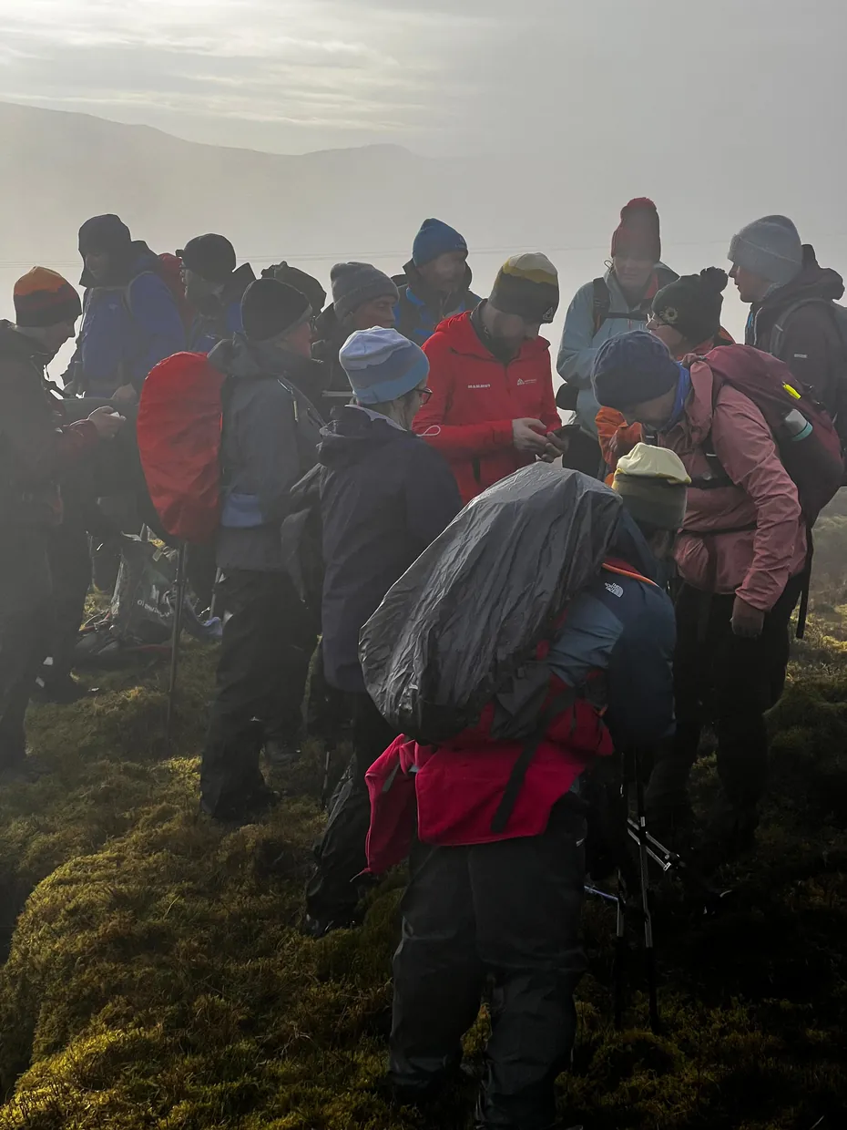 Hikers adding layers below a ridge before winter wind